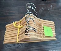 Stack of ten natural wood hangers with chrome hooks