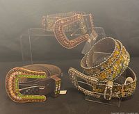 Three belts displayed on acrylic stands