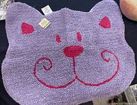 Purple cat-shaped mat with tag visible