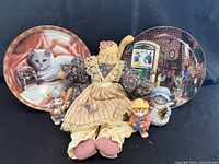 Group shot of cloth cat doll, two decorative plates, three ceramic cat figurines