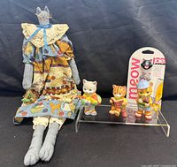 Group shot of fabric cat doll, three Bronson cat figurines, sealed Joie Meow bag ties