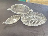 Three clear pressed glass trays arranged together