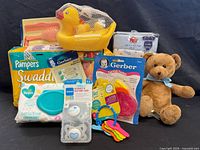 Group shot of all baby items including diapers, wipes, toys, clothing and accessories