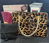 Group shot showing leopard handbag, black purse, folding fan, boxed JOI makeup mirror, sealed cotton squares