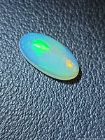 Top view of oval cabochon opal displaying green and orange play-of-color