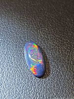 Front view of oval black opal showing multicolour fire