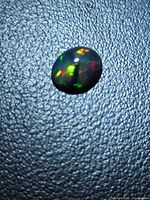 Top view of oval black opal displaying play of color