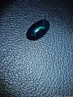 Oval black opal cabochon showing green and blue play of color