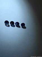 Four round faceted blue sapphires lined on white surface