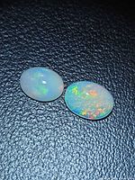 Two oval Ethiopian opal cabochons on black background showing play-of-color
