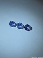 Three round violet-blue faceted gemstones on light background