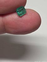 Emerald on fingertip showing size, color and octagon shape