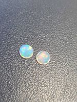 Pair of round faceted opals on dark background