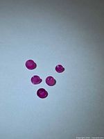 Five loose round pink-red rubies on white background