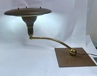 Full view of lamp showing saucer shade, brass arm, square base
