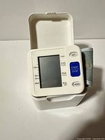 Front view of wrist blood pressure monitor showing LCD, buttons, cuff and case