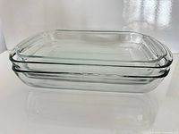 Three stacked clear glass rectangular pans showing side profile and handles