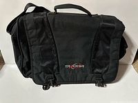 Front view of black Tracker laptop bag showing logo, flap and buckle closures