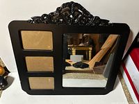 Front view showing mirror pane, three photo slots, and ornate crest