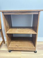 Front view of the laminate rolling shelf unit showing two shelves and casters