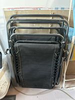 Stacked folded zero-gravity chairs showing fabric, frame, and missing armrest