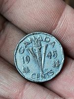 Reverse of 1945 Canada Victory nickel showing torch, V, maple leaves, date, denomination