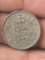 Reverse of 1957 One Shilling coin showing crowned shield, date, denomination