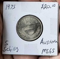 Reverse side of 1975 Austria 5 Schilling coin showing shield, denomination and laurel sprigs, MS65 and price noted on holder