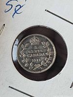 Reverse of 1911 5-cent coin in flip showing wreath and date