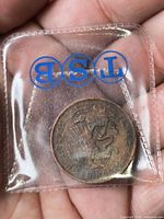 Coin front visible through clear sleeve showing eagle and snake emblem