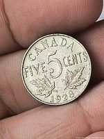 Reverse of 1928 Canada 5-cent coin showing denomination, maple leaves and date