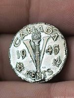 Reverse of 1945 Canada Victory nickel showing V, torch, date and maple leaves