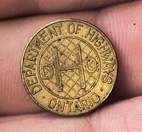 Obverse side of brass token showing Department of Highways Ontario text and large H