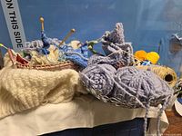 Metal basket with lavender yarn, twine spool, yellow thread, knitting needles visible