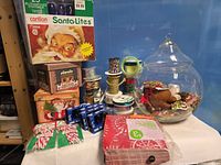 Group shot of entire lot showing light set, village boxes, ribbon spools, fabric linens, blue light boxes, glass jar with ornaments