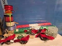 Stacked ribbon spools, sealed wrap rolls, cardinal decorations, jar of gems