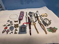 Overall lot view showing watches, pins, bracelet, beaded sheath