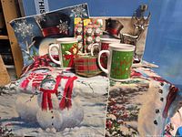 Overall lot view showing cushion covers, mugs, ribbon, cupcake picks package, reindeer candle holder