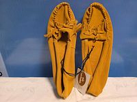 Top view of both moccasins showing leather suede upper, fringe bow, tag attached