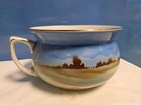 Side view showing chamber pot profile, handle, landscape motif