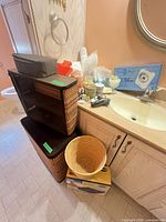 Overall view of hamper, shelf, waste bin, sink area with personal care items