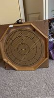 Full view of octagonal wooden Crokinole board leaning against its original cardboard box
