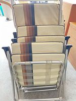 Stacked view of five aluminum framed chairs showing striped vinyl cushions