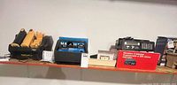 Shelf view showing Garmin GPS units in cradle, blue battery charger, red boxed RadioShack scanner and loose scanner unit