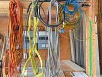Assorted cords, conduits, rope and wires hanging from garage rack