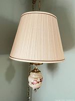 Overall view of hanging swag lamp showing shade, porcelain floral base, brass fittings and chain