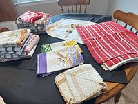 Overview of stacked tea towels, place mats and pot holders on table