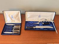 Two presentation cases; left contains six steak knives, right contains carving knife, fork and sharpening steel