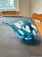 Full view of blue hand-blown ornament showing white inclusions and clear hanging loop