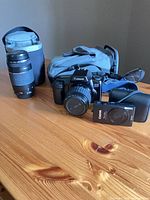 Group showing EOS 1000F with 35-80mm lens, 75-300mm lens in padded case, PowerShot camera with fitted case, shoulder bag